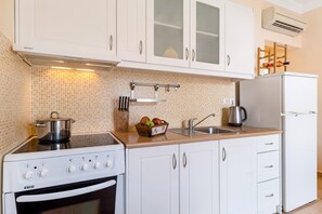 Una cocina con armarios blancos, estufa, lavabo y refrigerador.