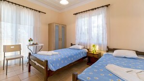 Une chambre avec deux lits, une chaise, une petite table et une armoire.