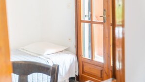 Een slaapkamer met een bed, een houten deur en een raam.