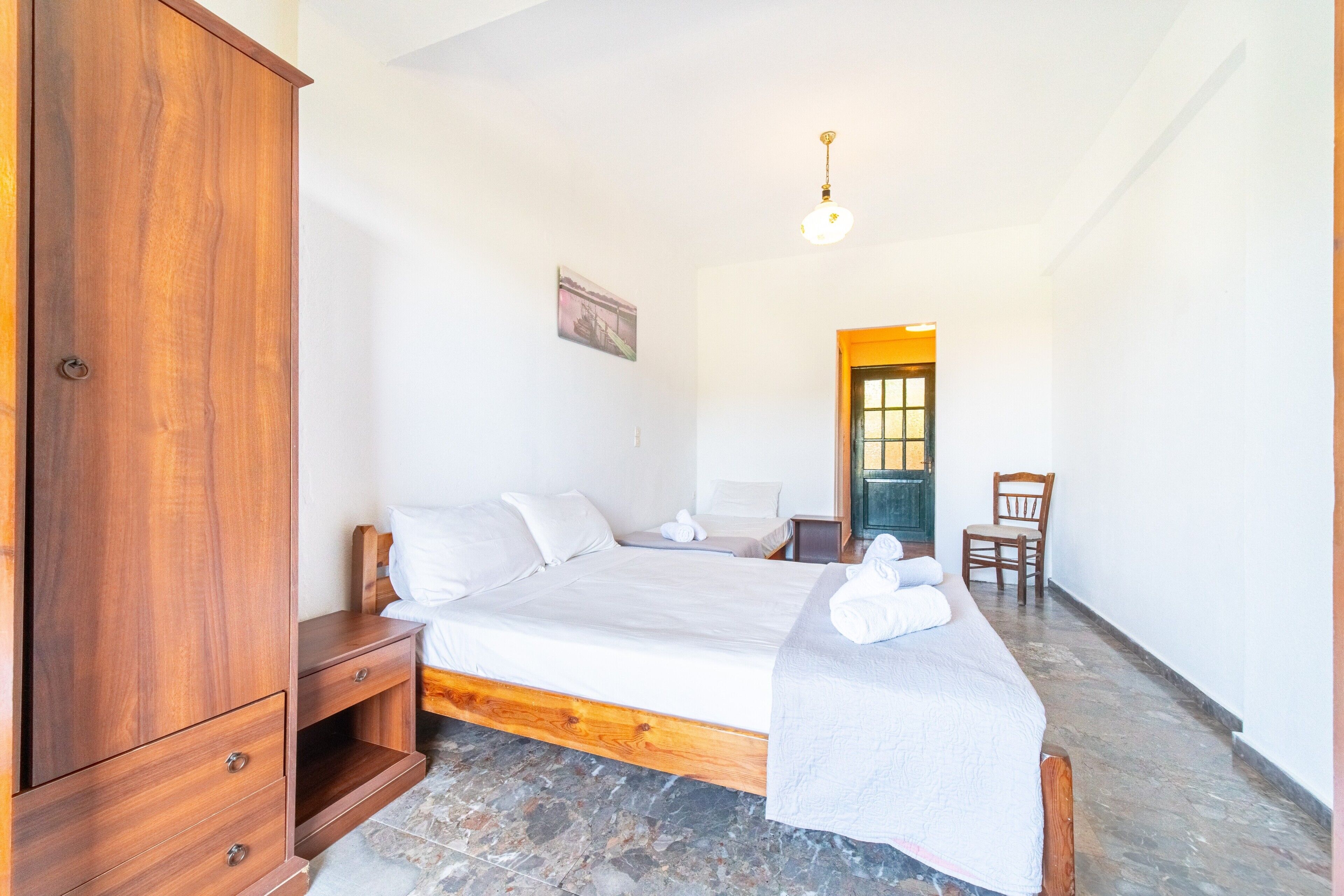 A bedroom with a bed, wooden wardrobe, and a chair.