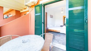 Habitació amb un llit, una taula, cadires, una escala i una porta.