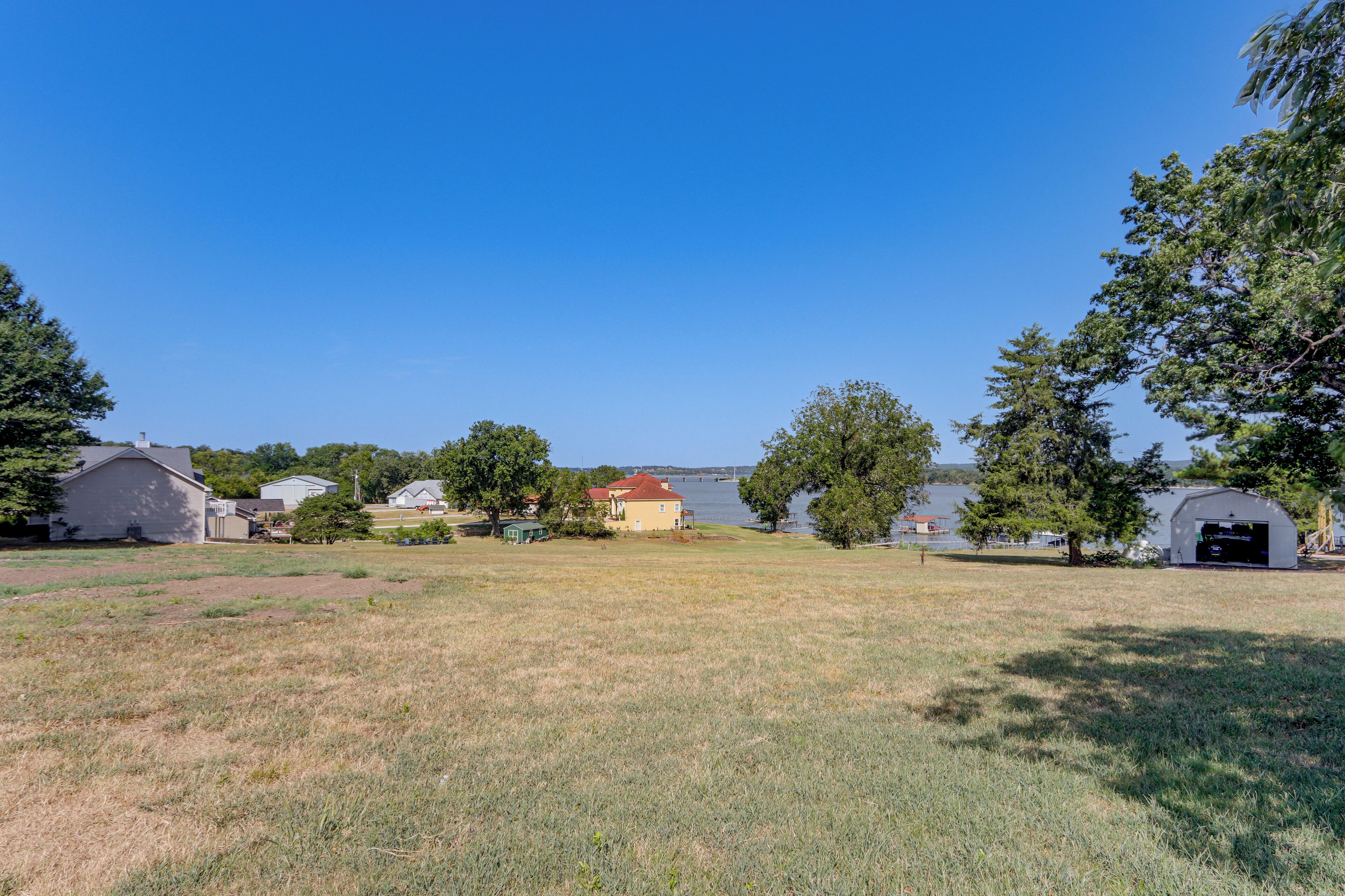 A grassy field with a lake and buildings in the background.