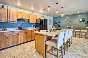 A modern kitchen with wooden cabinets, a central island with bar stools, and pendant lighting.