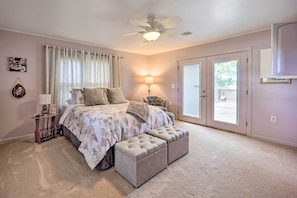 A bedroom with a bed, a nightstand, a lamp, a ceiling fan, and a sliding glass door leading to a balcony.
