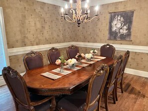 A dining room with a wooden table, six chairs, and a chandelier.