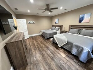 A bedroom with two beds, a dresser, and a ceiling fan.
