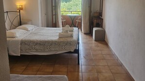 Ein Schlafzimmer mit Bett, Stuhl, Tisch, Fernseher und Blick auf Grünflächen.
