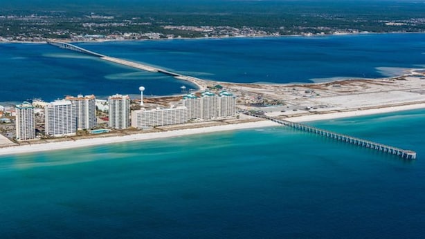 A coastal resort with high-rise buildings, a beach, and a pier extending into the water.