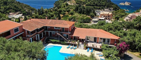 A hotel with a swimming pool, terraced balconies, and views of the sea.