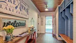 A hallway with a welcome sign, a vintage sign reading "Lake House," and a "Family Rules" sign.