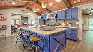A spacious kitchen with a large island, bar stools, and a farmhouse sign.