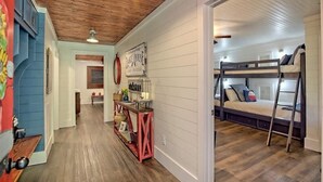 A hallway leading to a bunk bed room with a wooden ceiling and a welcome sign.