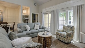 A spacious living room with a grey sofa, patterned armchair, and a round coffee table.