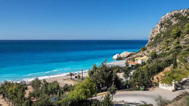 A coastal view with a beach, a restaurant, and a rocky hillside. - Apartment in a Hotel 'Sunset Premium Studio 7' with Sea View, Shared Pool, & Wi-Fi (Lefkada)