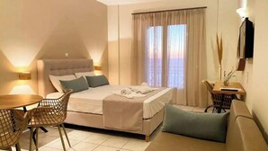 A bedroom with a bed, a sofa, a dining table, and chairs. - Apartment in a Hotel 'Sunset Premium Studio 7' with Sea View, Shared Pool, & Wi-Fi (Lefkada)