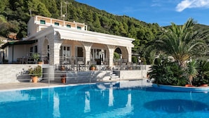 A poolside area with a building featuring arched windows and a covered patio. - Apartment in a Hotel 'Sunset Premium Studio 7' with Sea View, Shared Pool, & Wi-Fi (Lefkada)