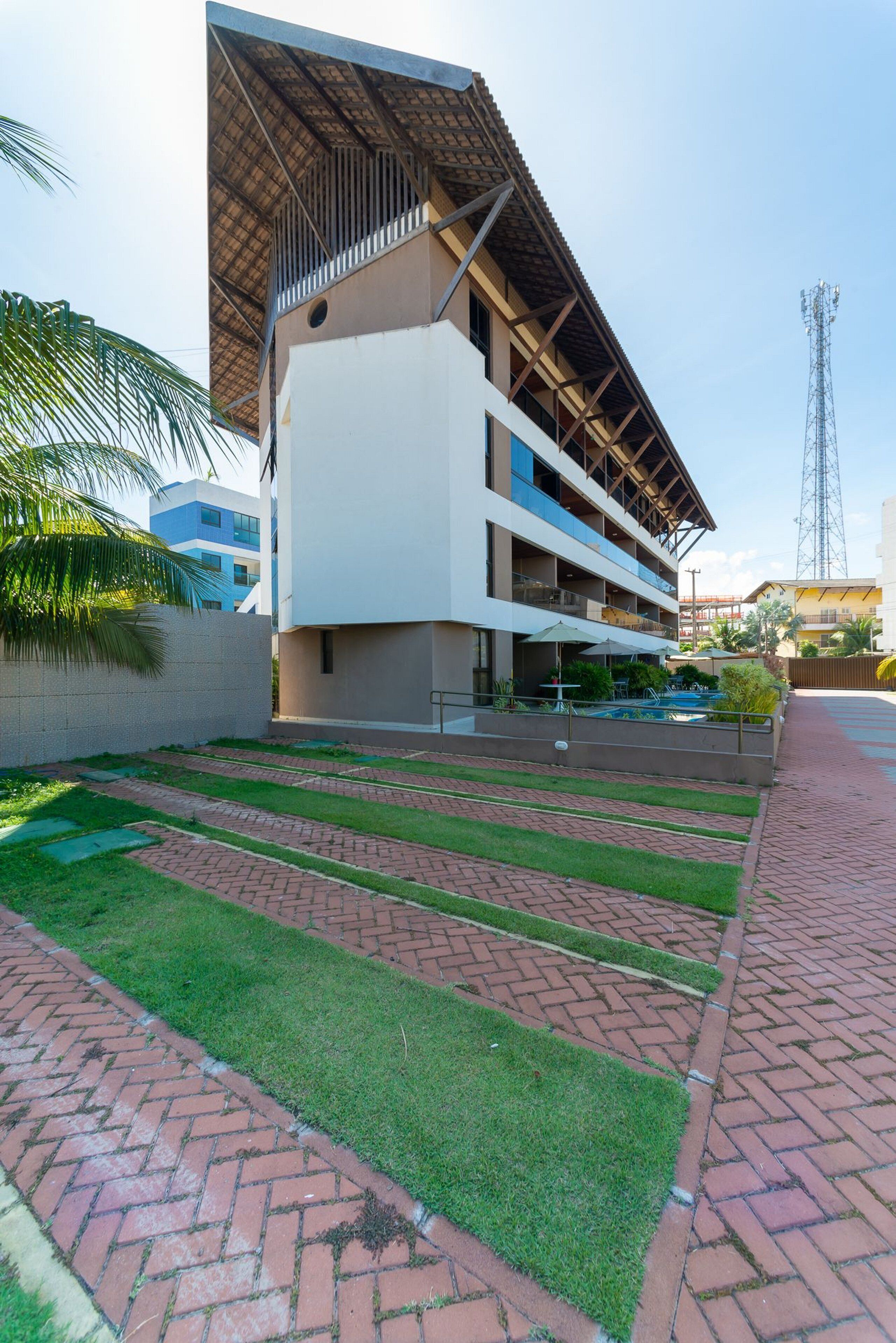 Un hotel moderno con techo plano, varios balcones y zona de piscina.