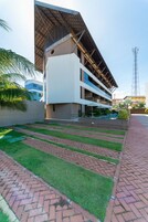 Un hotel moderno con techo plano, varios balcones y zona de piscina.