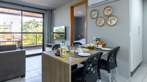 A dining area with a wooden table, black chairs, and a TV mounted on the wall. - Praia Central Porto de Galinhas (Ipojuca)