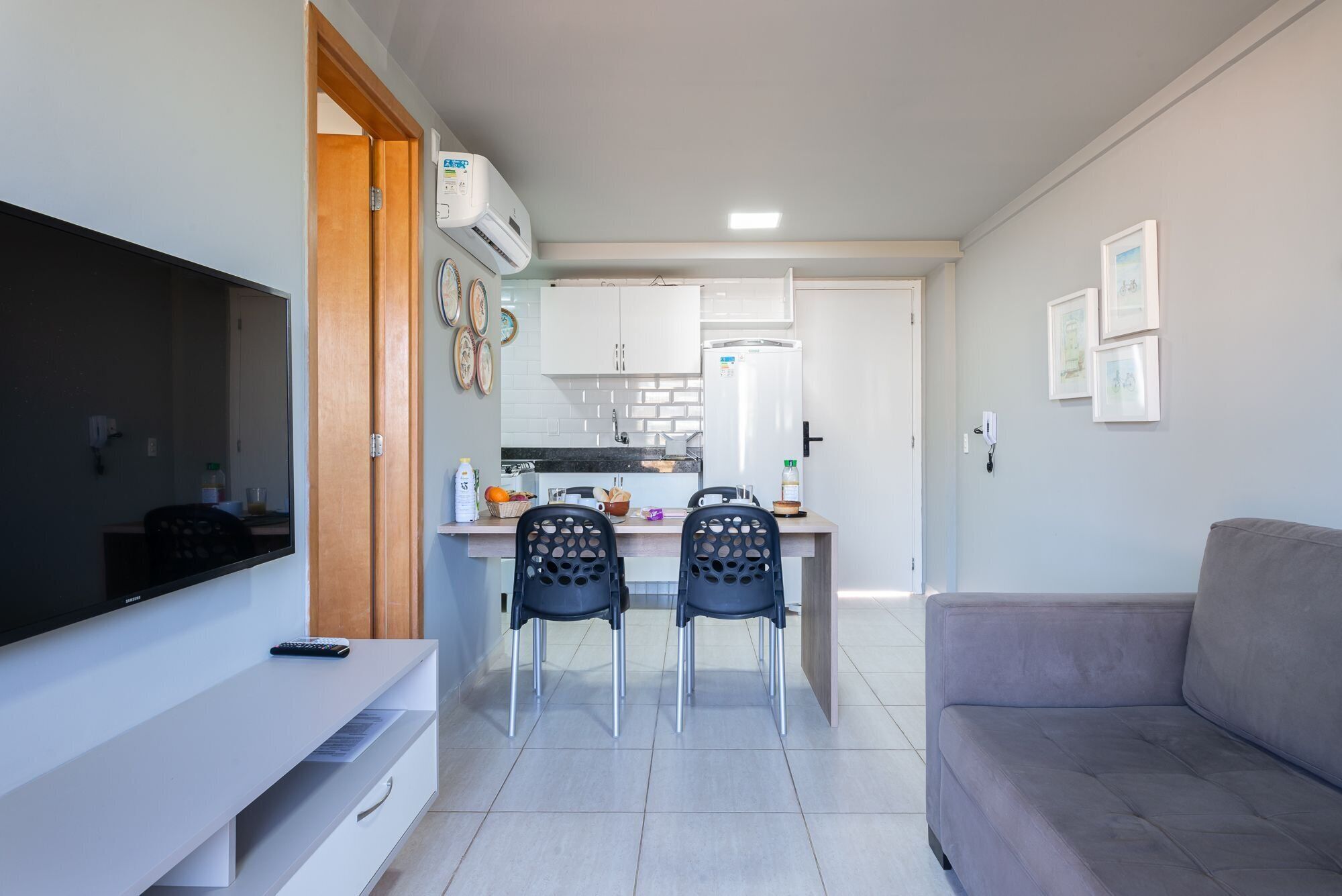 A compact living space with a kitchenette, a dining area with two chairs, a sofa, and a flat-screen TV.