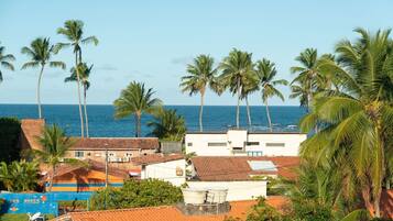 A coastal town with palm trees, a clear blue sky, and the ocean in the background.