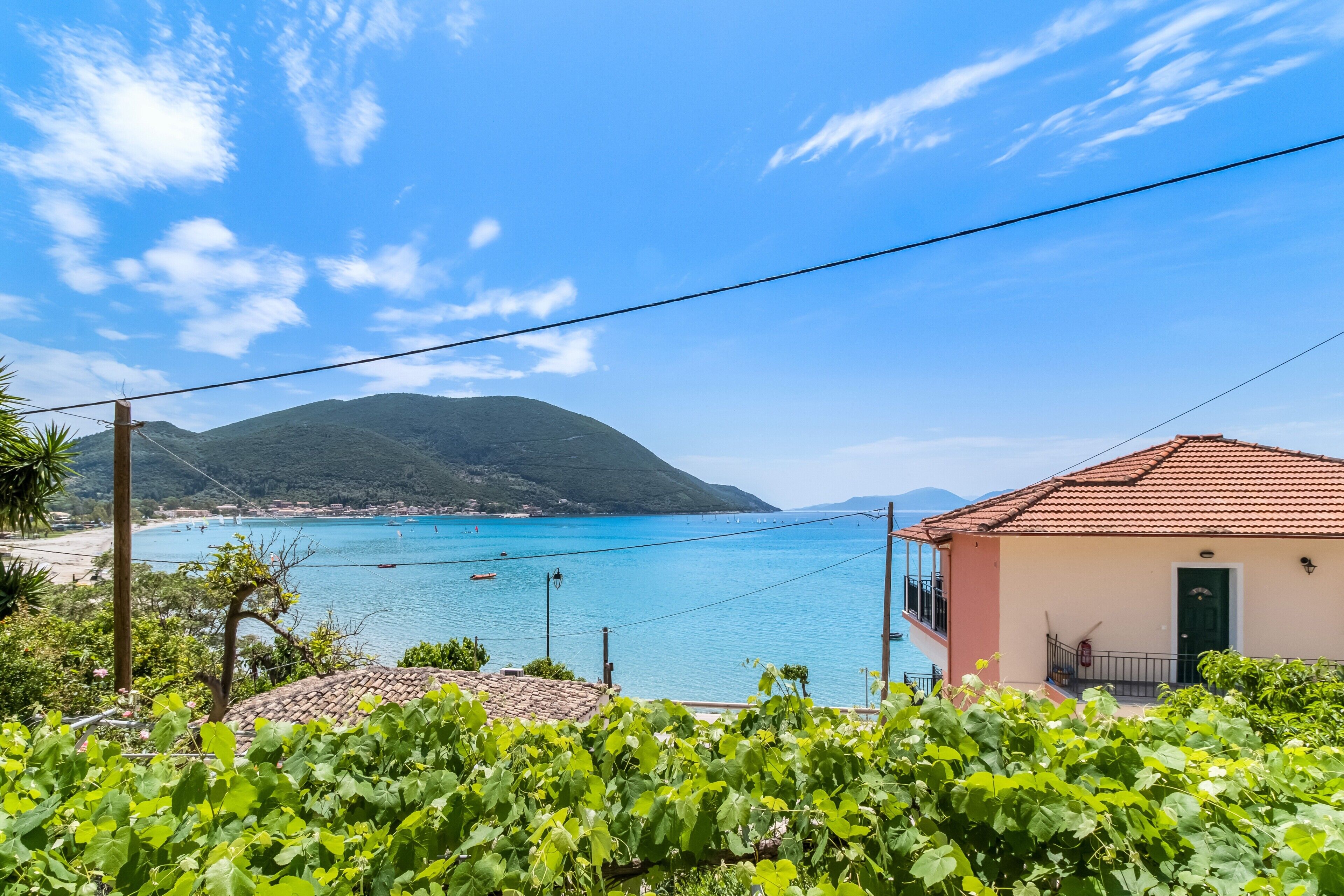 A coastal view with a building, clear sky, and distant mountains.