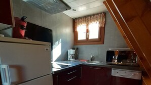 A compact kitchen with a refrigerator, microwave, coffee maker, and dishwasher. - Chalets cocody norvégien (Jausiers)