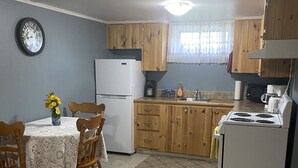 Une cuisine compacte dotée de meubles en bois, d’un réfrigérateur, d’un four à micro-ondes et d’une table à manger avec des chaises.