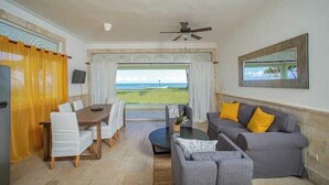 Ein Wohnzimmer mit Esstisch, Sofa und Blick auf den Ozean.