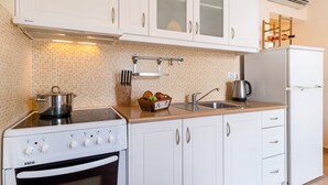 Une cuisine avec des meubles blancs, une cuisinière, un évier et un réfrigérateur.