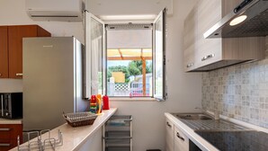 Une cuisine compacte dotée d’un réfrigérateur intégré, d’une fenêtre offrant une belle vue et d’un petit évier.