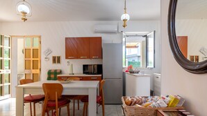 Une cuisine avec des meubles en bois, un réfrigérateur et un coin repas comprenant une table et des chaises.