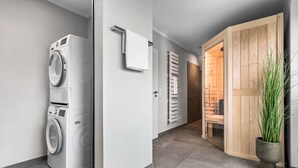 A modern laundry area with a washing machine, a drying rack, and a wooden door leading to a sauna. - Momme II - close to the North Sea and the beach, sauna, terrace, modern (Büsum)