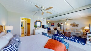 Une chambre d’hôtel avec un grand lit, un ventilateur de plafond, une télévision, un canapé et un coin repas offrant une vue agréable.