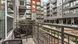 A multi-story residential building with balconies, outdoor seating, and a landscaped garden area. - Boulevard Stays Elegant 1BR Pool, Gym, Parking (Richardson)