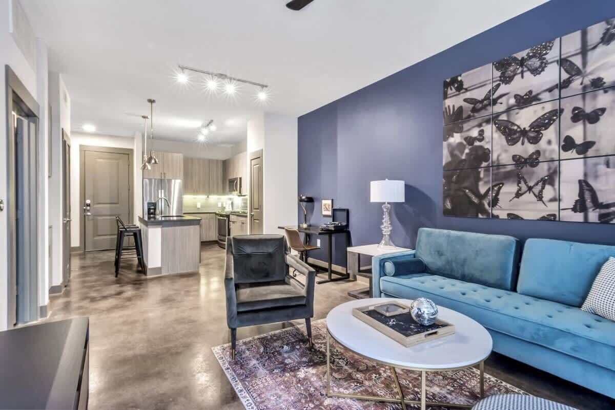 Uma sala de estar moderna com um sofá azul, uma mesa de centro e um painel decorativo com uma borboleta.