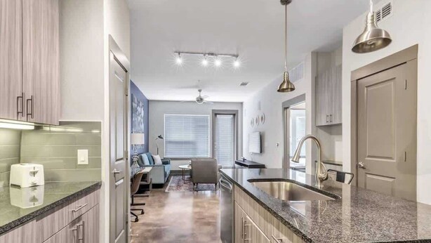 A modern kitchen with granite countertops, stainless steel appliances, and a central island. - Boulevard Stays Elegant 1BR Pool, Gym, Parking (Richardson)