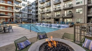 A multi-story building with a swimming pool, outdoor seating, and a fire pit. - Boulevard Stays Dashing 1BR Suite Pool, Parking Gym G (Richardson)