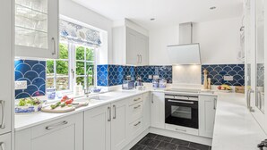 Una cocina moderna con armarios blancos, un horno negro y un salpicadero de azulejos azules.