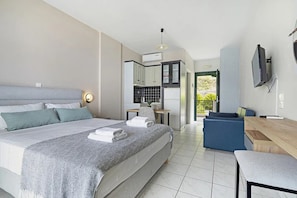 Une chambre d’hôtel moderne équipée d’un lit, d’un bureau, d’une chaise, d’une télévision et d’une kitchenette.