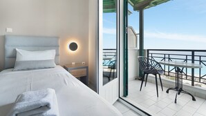 A modern hotel room with a bed, a small bedside table, a round wall light, and a balcony with a table and chairs. - Apartment in a Hotel 'Sunset Premium Studio 5' with Sea View, Shared Pool, & Wi-Fi (Lefkada)