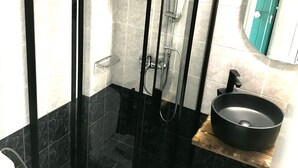 A shower enclosure with a glass door, a sink with a black basin, and a mirror above the sink. - Apartment in a Hotel 'Sunset Premium Studio 3' with Sea View, Shared Pool, & Wi-Fi (Lefkada)