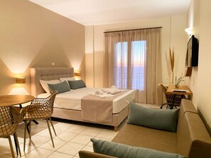 Una habitación de hotel con cama, sofá, mesa de comedor y televisor.