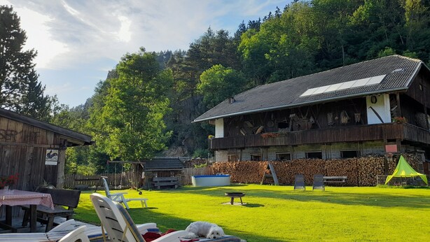 Een rustieke chalet met een houten gevel, een balkon met uitzicht op het bos, en een verzorgd gazon.