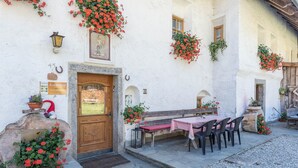 A traditional building with a wooden door, a bench, and a table with chairs outside. - Oberwieserhof Apartment 3 in South Tyrol with Shared Garden and Wi-Fi (St.Lorenzen)
