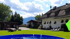A swimming pool with a ladder, surrounded by a grassy lawn and a building with a sloped roof. - Oberwieserhof Apartment 3 in South Tyrol with Shared Garden and Wi-Fi (St.Lorenzen)