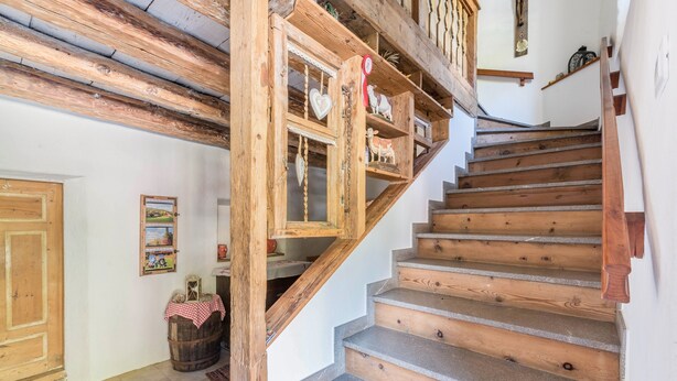 A wooden staircase with a rustic design, a wooden door, and a small table with a checkered tablecloth. - Oberwieserhof Apartment 3 in South Tyrol with Shared Garden and Wi-Fi (St.Lorenzen)