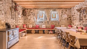 A rustic dining area with stone walls, wooden beams, a long table, and benches. - Oberwieserhof Apartment 3 in South Tyrol with Shared Garden and Wi-Fi (St.Lorenzen)