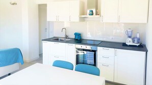 A compact kitchen with white cabinets, a sink, a stove, and a blender. - Affittimoderni Castelsardo La Gemma (Castelsardo)