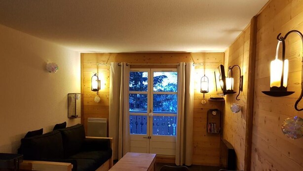 Una habitación acogedora con detalles de madera, un sofá, una mesa y dos sillas.